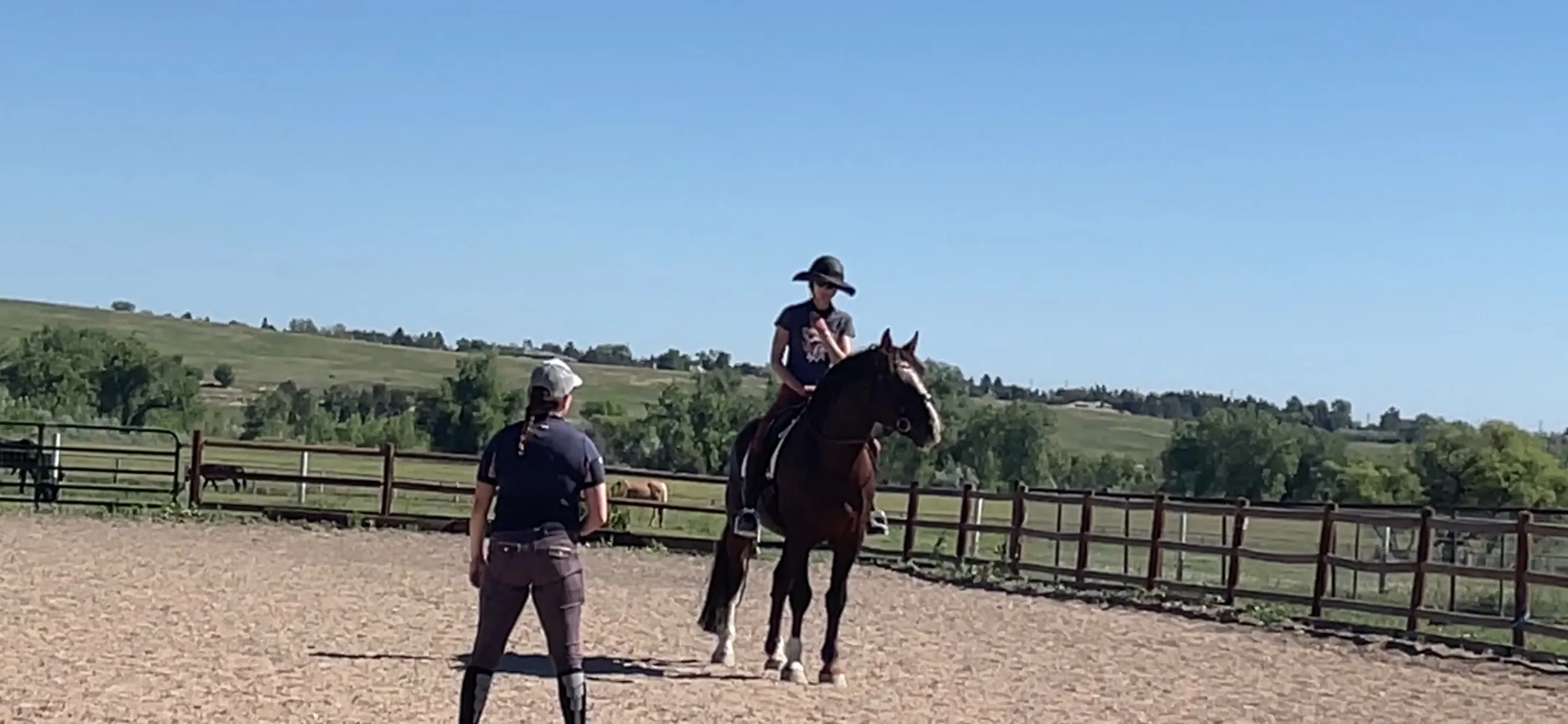 A lesson in the outdoor arena — instructor coaching a horse and rider